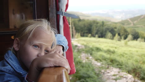 child looking out of a train window at scenic mountain views