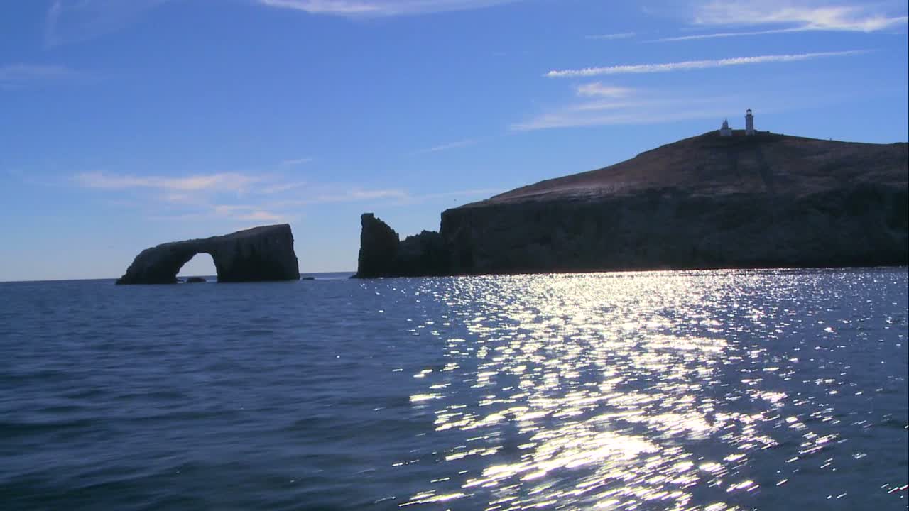 다가오는 배에서 볼 수 있는 등대와 상징적인 자연 다리가 있는 아나카파 섬의 와이드 샷
