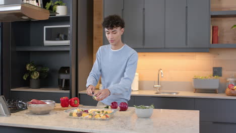 preparing vegetables, young man chopping ingredients in modern kitchen at home