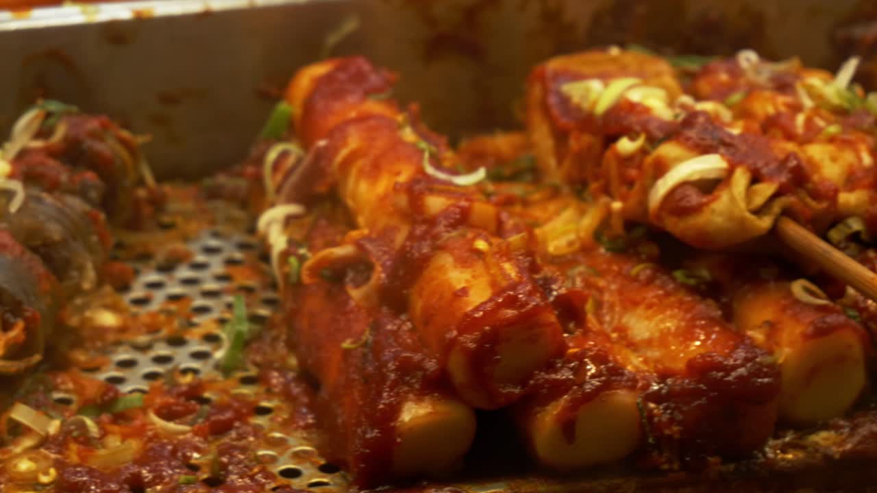 Fish Cake Skewers With Spicy Red Sauce And Chopped Green Onions. Korean Street Food. closeup sliding shot