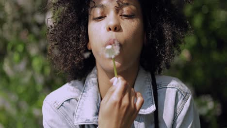 woman blowing on dandelion