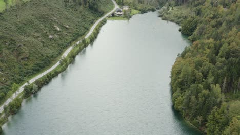 Presa-Del-Embalse-De-Freibach-Con-El-Restaurante-De-Especialidades-Griegas-Stausewirt-En-El-Borde-Lejano,-Tiro-De-Revelación-De-Inclinación-Aérea-Hacia-Arriba