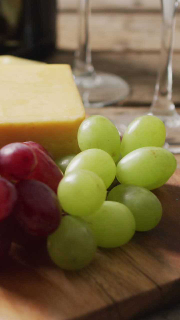 vídeo de diversos quesos, uvas y vasos de vino en superficie de madera