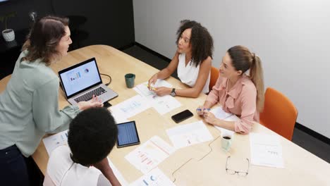 Diversas-Mujeres-De-Negocios-Hablando-Y-Usando-Una-Computadora-Portátil-En-Una-Reunión-De-Oficina,-En-Cámara-Lenta