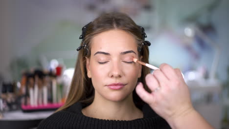 woman getting eyeshadow applied by a makeup artist