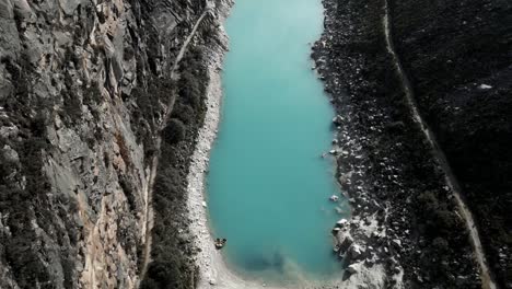 Antena-Sobre-Laguna-Paron-Agua-Turquesa-Lago-De-Los-Andes-Peruanos-Entre-Montañas-Y-Pico-De-La-Pirámide,-Destino-De-Viaje-De-Trekking-En-La-Cordillera-Blanca,-Perú