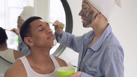 woman applying facial mask to a handsome black man 1