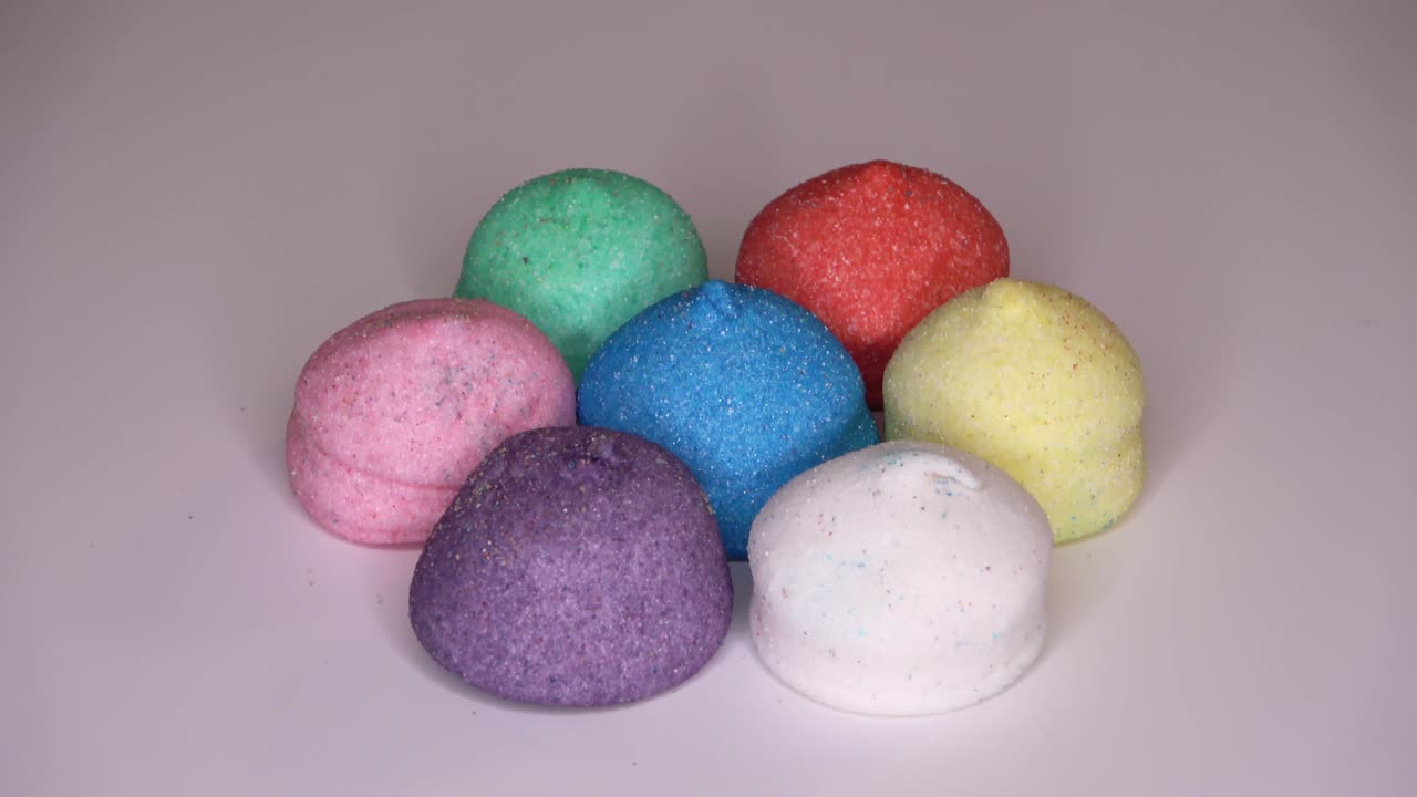 очень красочные конфеты с маршмеллоу на белом фоне, вращающиеся в круге - закручиваемые кадры.