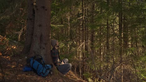 a man with a backpack resting in a forest