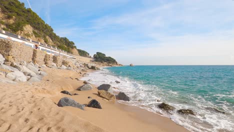 Schöner-Mediterraner-Sandstrand,-Maresme-Barcelona,-San-Pol-De-Mar,-Mit-Felsen-Und-Ruhigem-Meer-Und-Türkis,-Costa-Brava