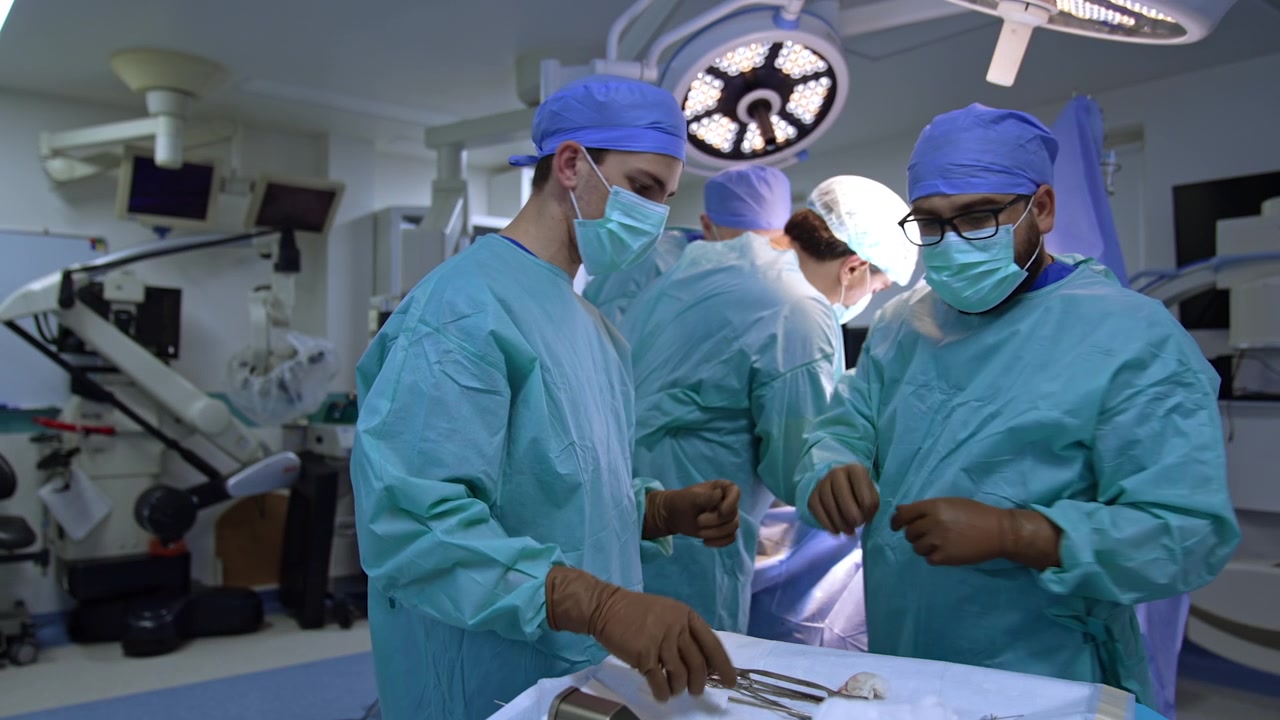 I chirurghi si rivolgono al carrello chirurgico con tutti gli strumenti necessari per la chirurgia traumatologica. L'assistente uomo sistema gli strumenti sul carrello