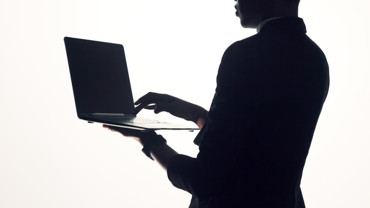 Silhouette of a person using a laptop