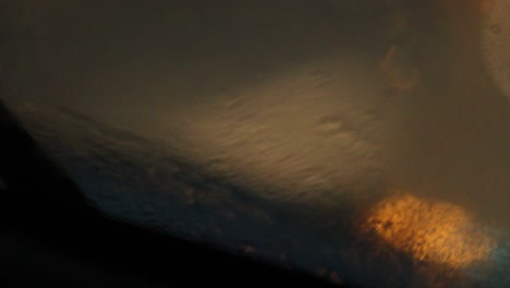 abstract bokeh lights while driving on road with windshield wipers cleaning rain out. city lights melancholic sensation in 4k