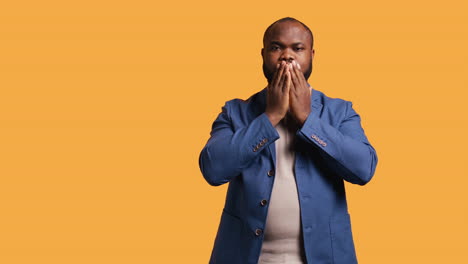 man covering eyes, ears and mouth with hands, studio background