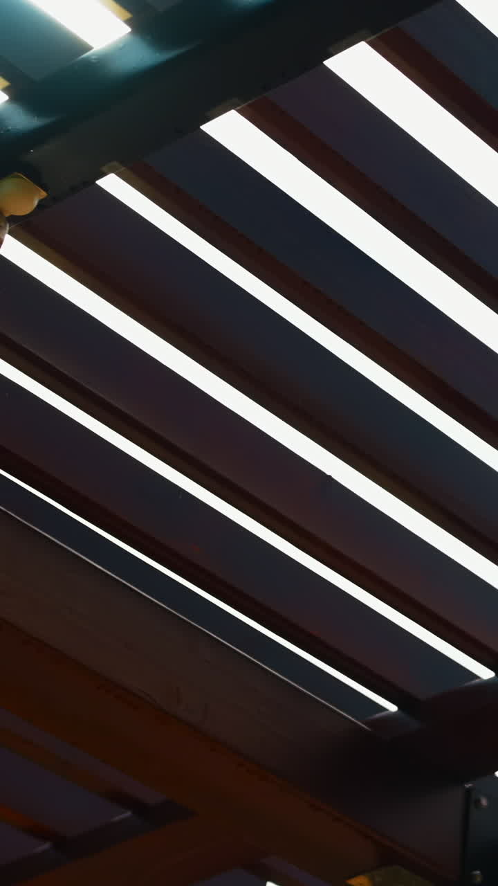 Luce solare che filtra attraverso le doghe di una pergola in legno.