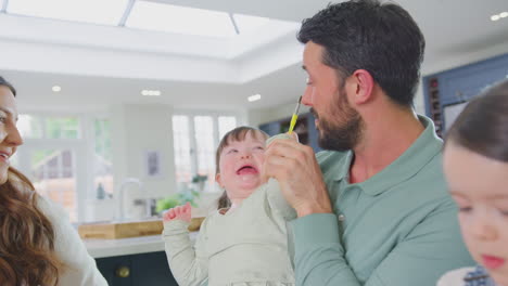 Una-Familia-Con-Una-Hija-Con-Síndrome-De-Down-Sentada-Alrededor-De-Una-Mesa-En-Casa-Haciendo-Manualidades-Haciendo-Tarjetas-Juntas