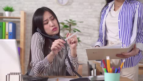 young asian woman office worker is engaged in personal affairs at the workplace in the office chatting on the phone and sawing nails