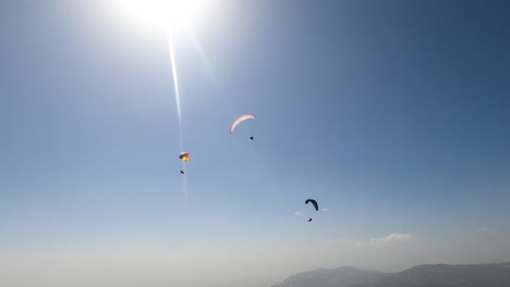 a group of three paragliders flying in slovenian mountains in sunny conditions when air is polluted by sand from sahara