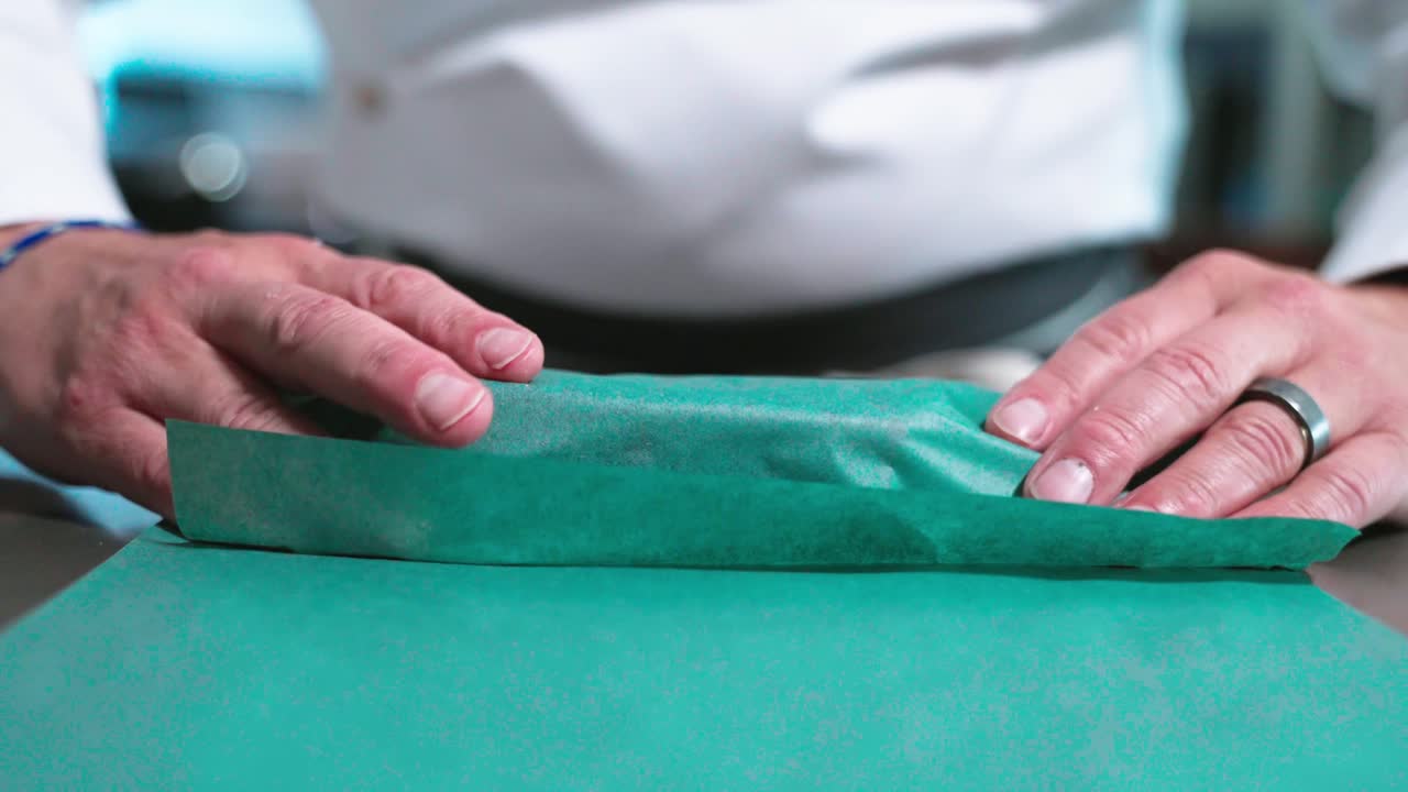 A static close-up shot captures a sushi chef wrapping a slab tuna fish, highlighting the precision and artistry involved in sushi preparation. Ideal for culinary, sushi, and food preparation content