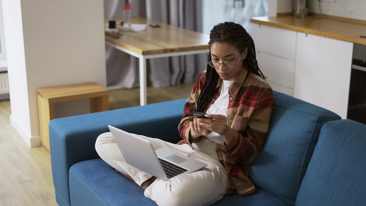Young african american holding credit card using a digital mobile device and buying online