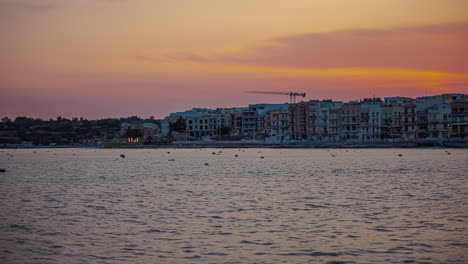 edificios de la ciudad costera de gzira, malta como el cielo al atardecer se desvanece al anochecer, timelapse