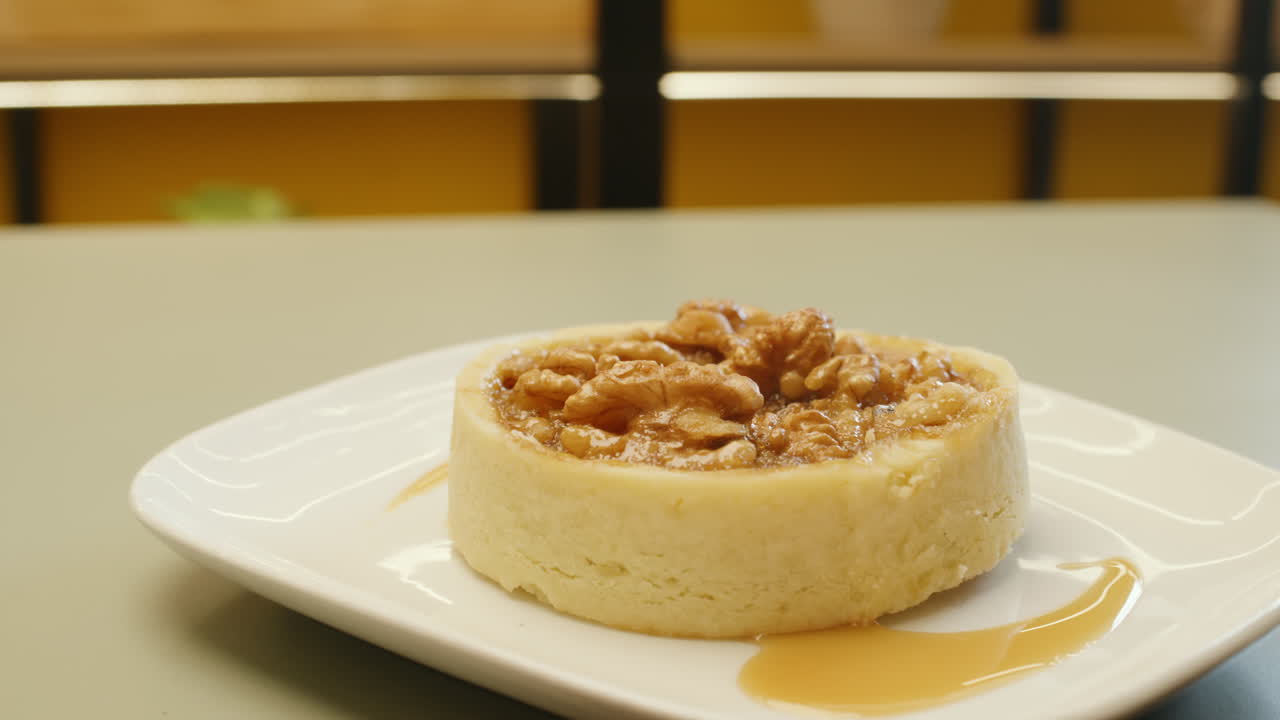 Panning shot of a cheesecake garnished with whole walnuts on top, highlighting its creamy texture and crunch