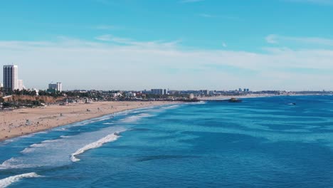 Slow-cinematic-shot-flying-over-the-pacific-ocean-and-Santa-Monica-Beach,-CA