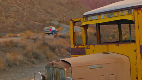 a car drives past an old abandoned school bus sitting on the side of the road.