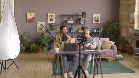 camera is recording a woman and man sitting at table while doing a podcast 3