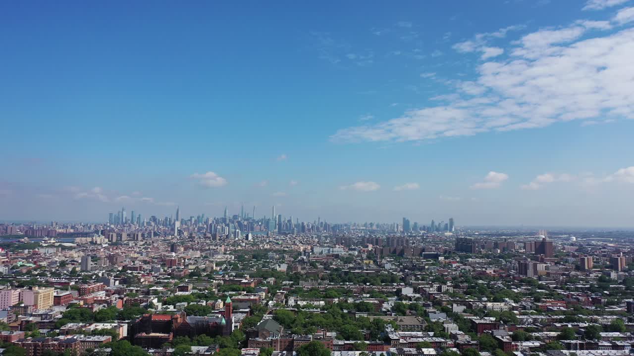 An aerial view over Bedford Stuyvesant, Brooklyn in NY. It is a sunny and clear day. The drone camera pans left to show the Manhattan skyline on the horizon in the distance.