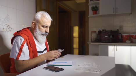 mature man who is worker calculating month-end bills and trying to pay them.