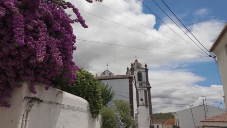 purple bougainvillea blooming in front of a church in a portuguese village