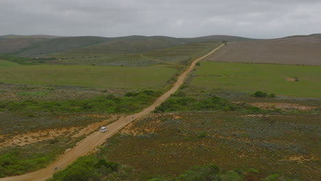 Aerial-view-of-car-driving-on-dirt-road-in-countryside.-Dusty-path-between-vast-fields.-South-Africa