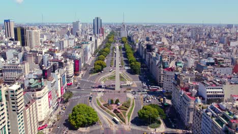 Vista-Aérea-Que-Establece-La-Avenida-9-De-Julio-Con-Un-Camino-De-árboles-En-Primavera,-Monumento-Obelisco-En-El-Centro-De-Buenos-Aires,-Argentina