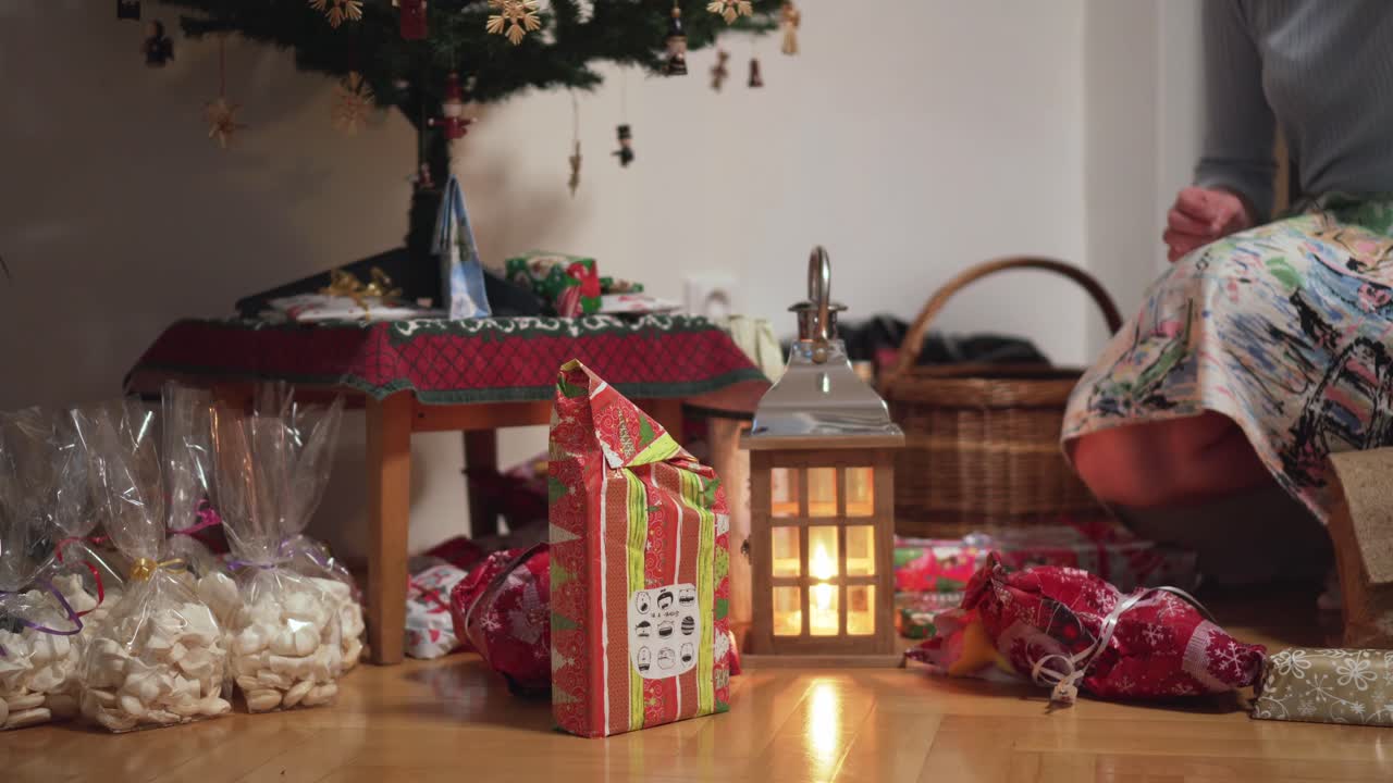 Christmas tree with pile of gifts and girl taking one, side view closeup