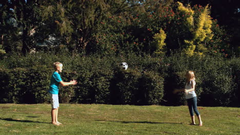 hermano feliz lanzando una pelota a una hermana en un parque