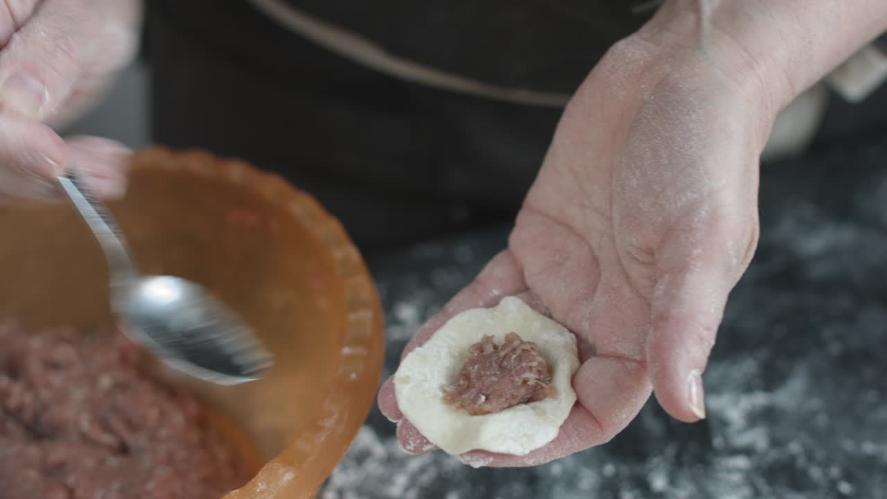 Two hands making meat dumplings.