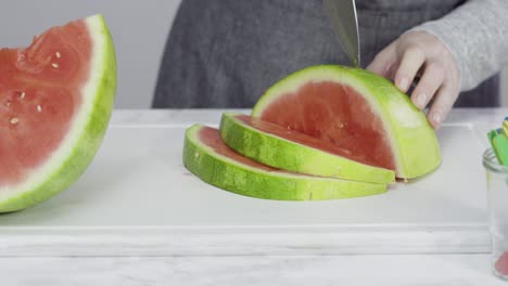 slicing red watermelon into small pieces