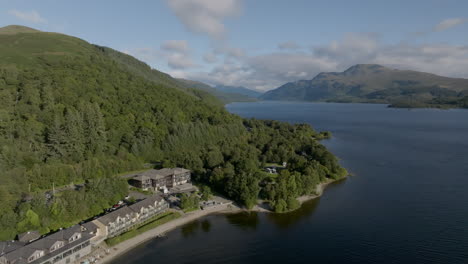 Toma-De-Seguimiento-Aéreo-Del-Lago-Lomond-Sobre-Luss-En-Dirección-Norte-Por-La-Carretera-A82