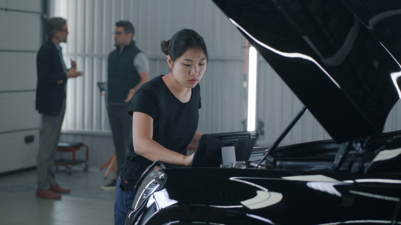 Female auto technician performs diagnostics on a car in a modern garage