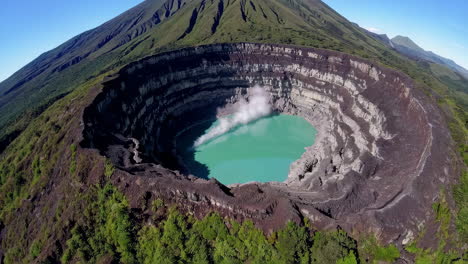 aerial view of a steaming turquoise crater lake in a volcano