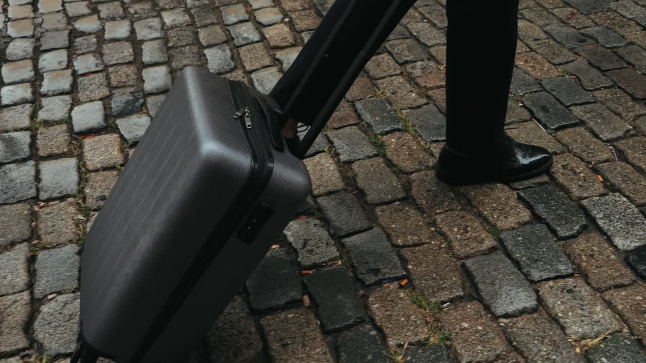 Turista con valigia in Spagna. Un viaggiatore con bagaglio e giacca da completo su una strada commerciale si dirige verso un hotel, un ufficio o un terminal aeroportuale, godendosi l'atmosfera vivace.