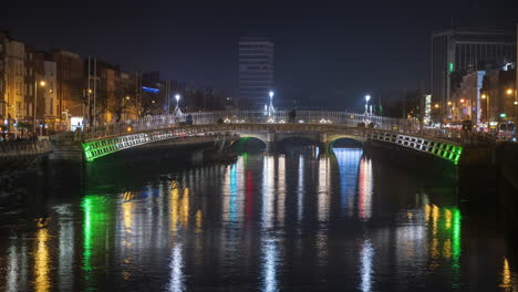 time lapse of nighttime road traffic and people walking over the historical bridge on liffey river in dublin city centre in ireland.