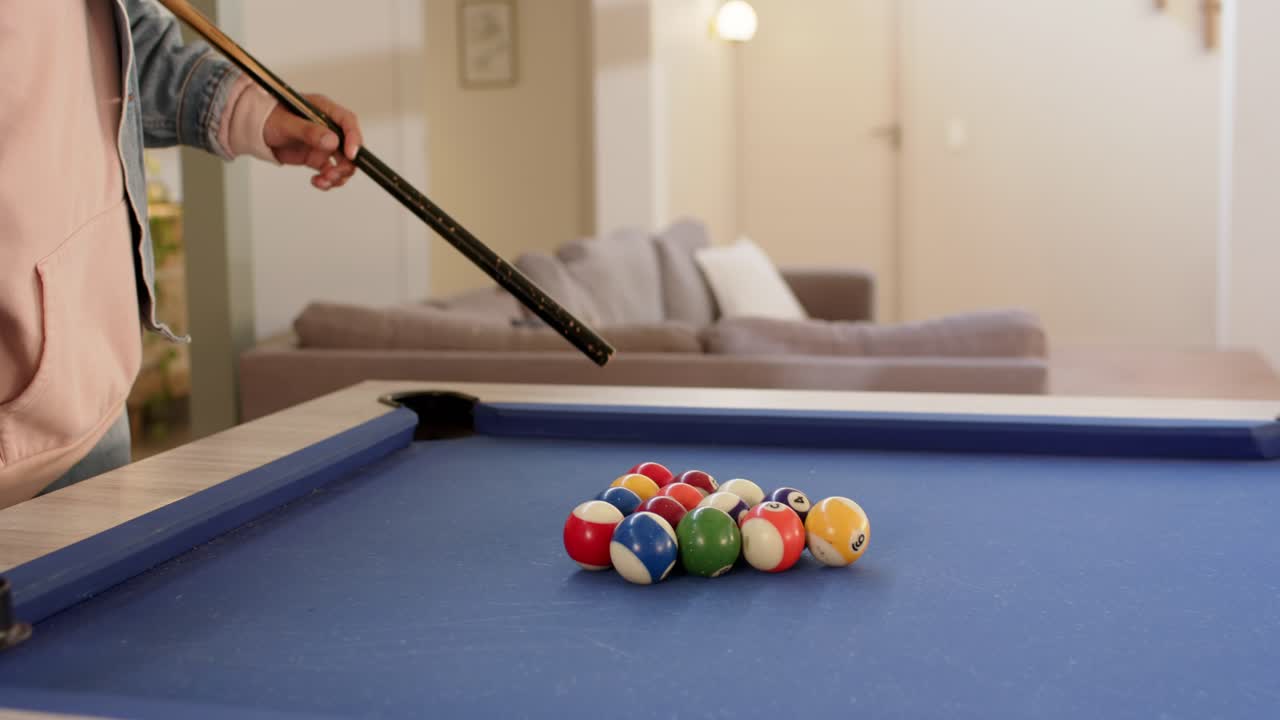 Man is entering frame and racking billiard balls on blue pool table for opening break shot