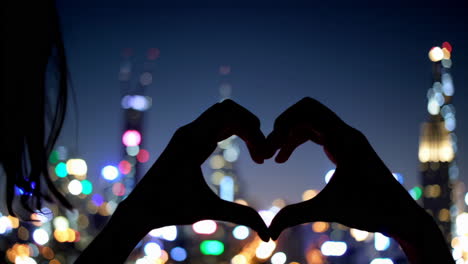 heart shape hands over city lights at night