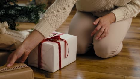 Young-caucasian-woman-putting-Christmas-gifts-under-Christmas-tree.