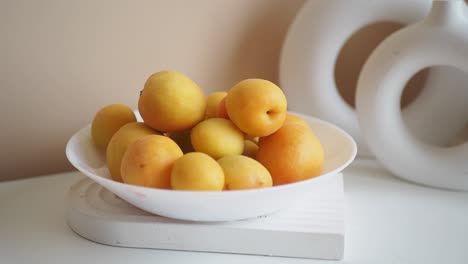 a bowl of fresh apricots on a white table