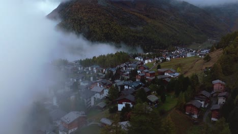 Moody-fog-Saastal-Saas-Fee-village-town-Switzerland-aerial-drone-foggy-cloudy-rainy-Larch-forest-beautiful-Fall-Autumn-Swiss-Alps-mountain-peaks-glacier-valley-Zermatt-The-Matterhorn-forward-reveal