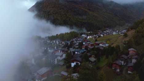 moody fog saastal saas fee village town switzerland aerial drone foggy cloudy rainy larch forest beautiful fall autumn swiss alps mountain peaks glacier valley zermatt the matterhorn forward reveal