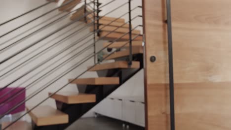 escalera flotante de madera y metal y puerta de madera en el interior de la casa moderna, cámara lenta